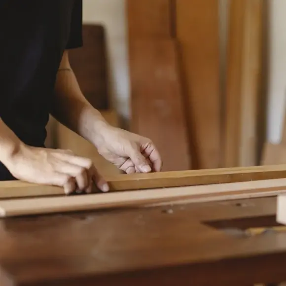 Hands shaping and aligning timber boards in a workshop