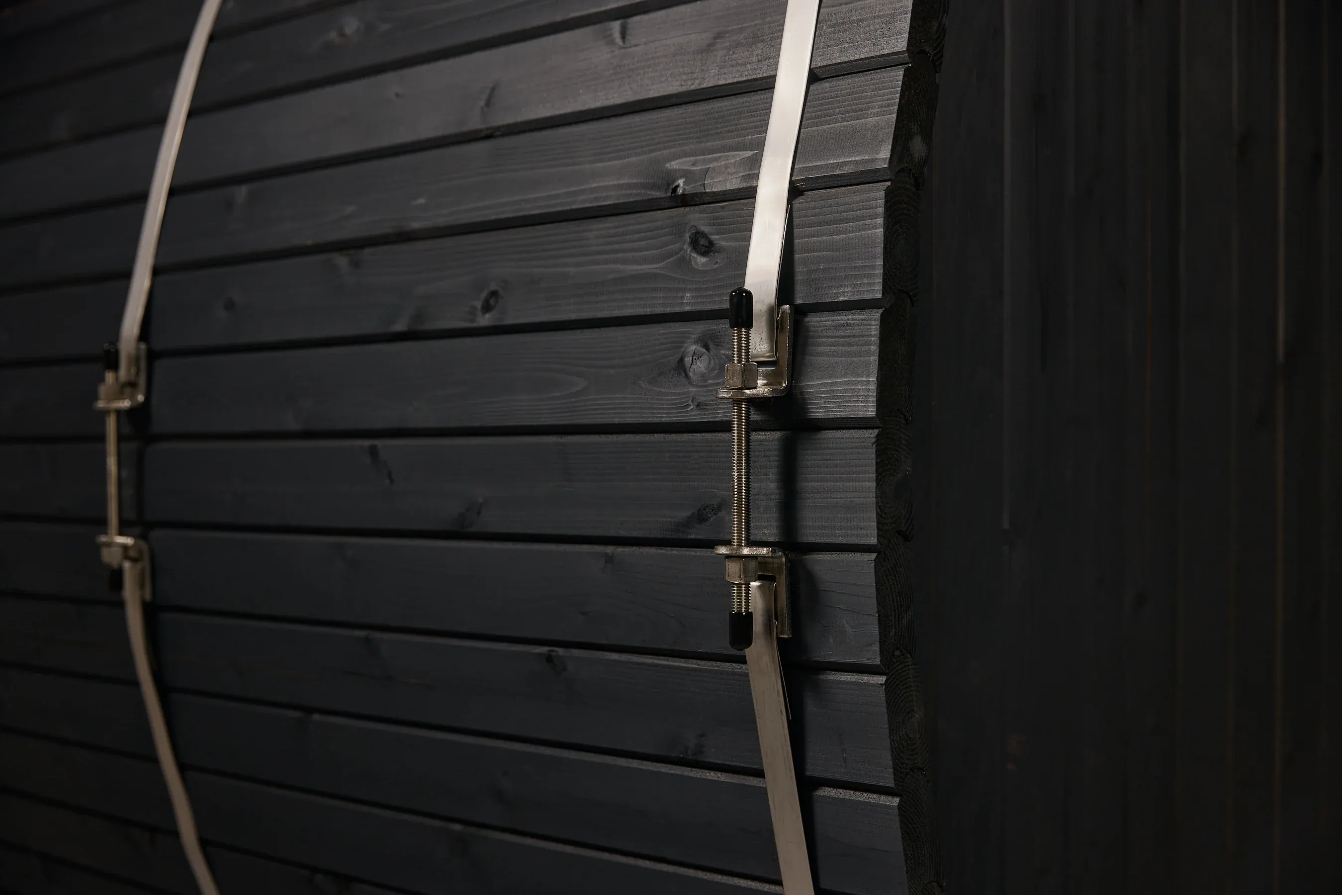 A close-up of dark sauna timber and a metal tensioning hoop