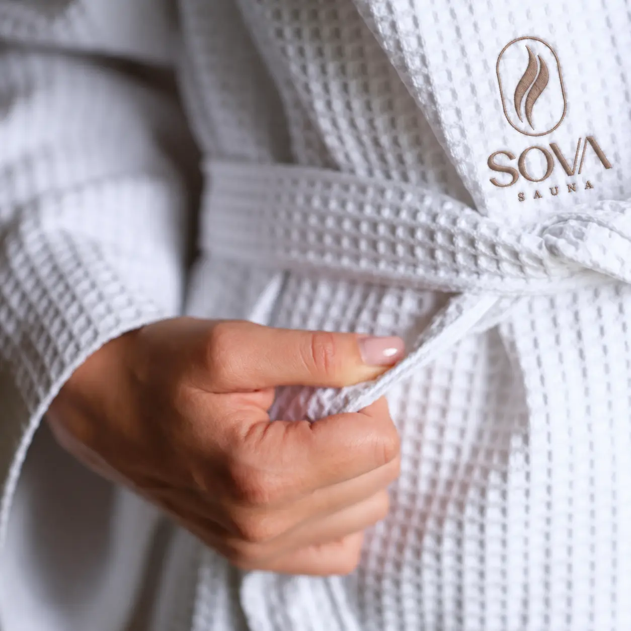 A guest fastening a white spa robe